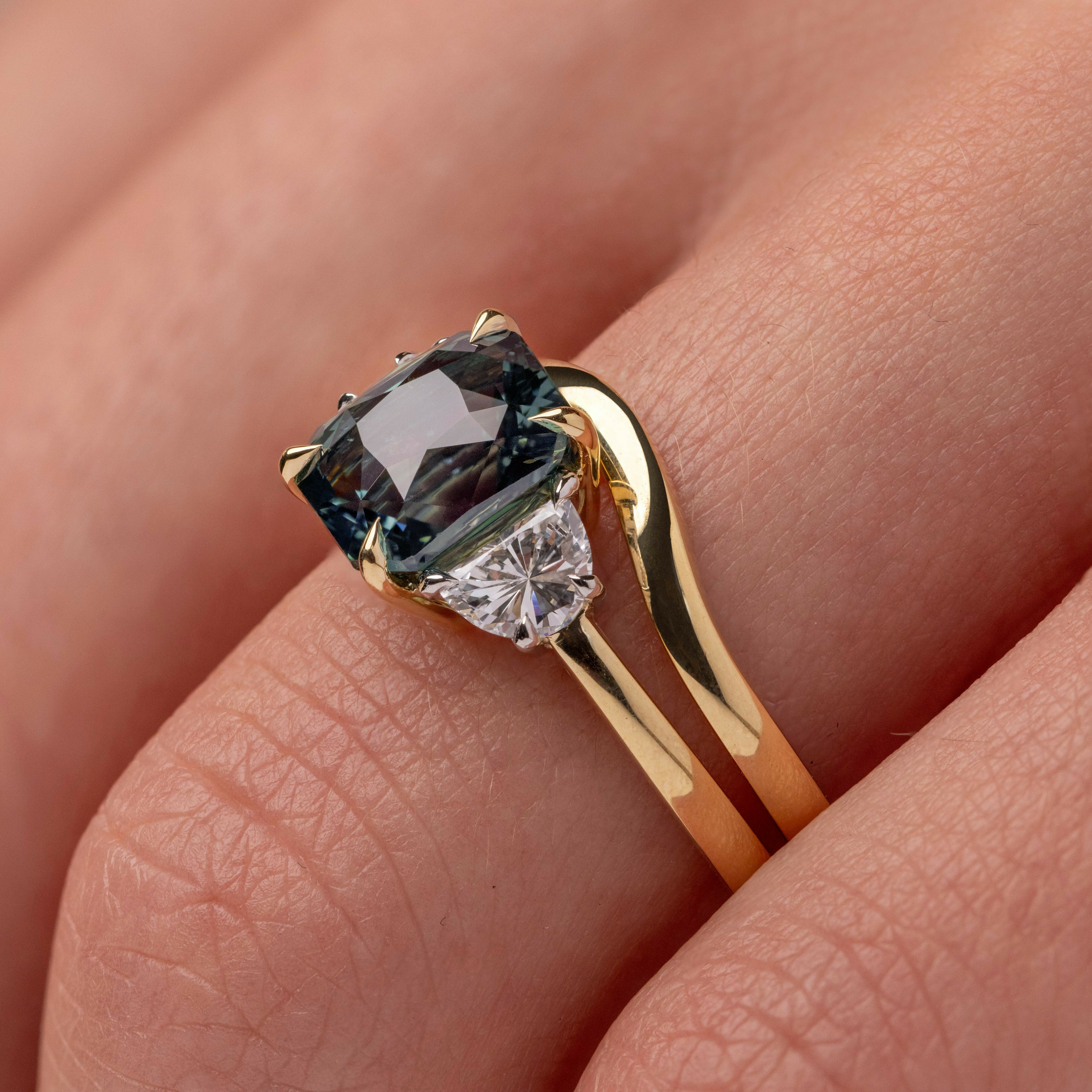 Teal sapphire engagement ring with a contour yellow gold fitted wedding ring