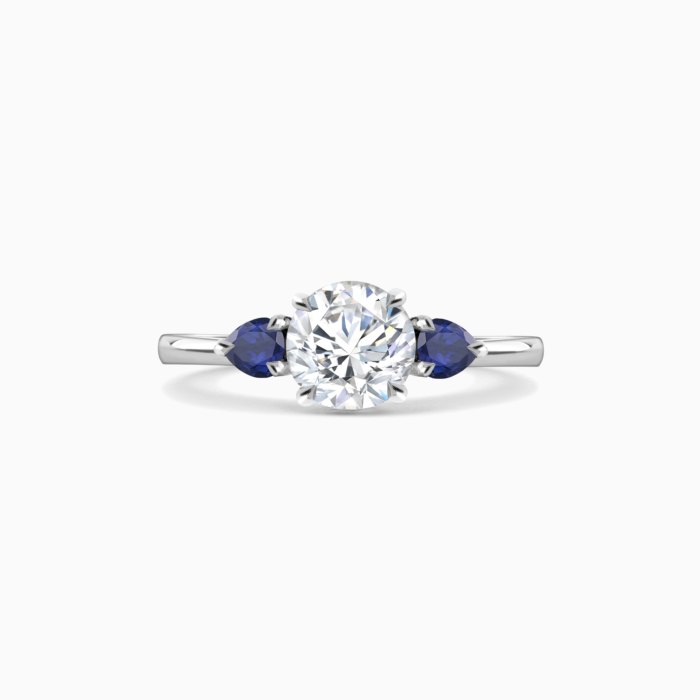 Dublin A diamond and sapphire trilogy ring featuring pear cut royal blue sapphire side stones set in platinum